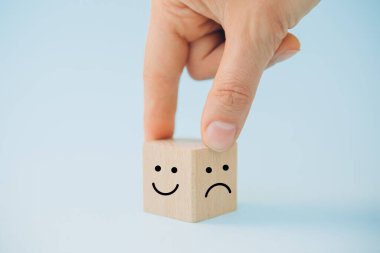 Kadın eli, gülen surat ve üzgün yüz simgesini tahta küpte, hizmet derecesi, tatmin konseptinde seç.