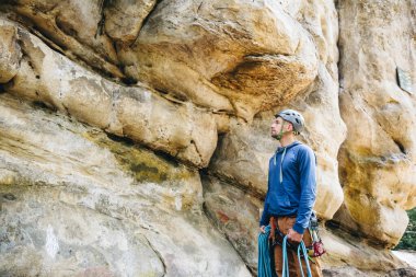 Güçlü bir tırmanıcı kemerinde ekipmanla halat tutuyor ve tırmanmaya hazırlanıyor.