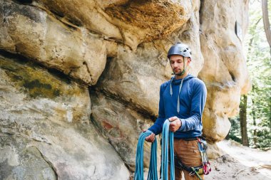 Güçlü bir dağcının yakın çekimi kemerinde ekipmanla halat tutarak tırmanmaya hazırlanıyor.