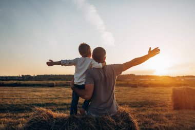 Baba ve oğul gün batımında parkta oynuyorlar. Aile, güven, koruma, bakım, ebeveynlik, yaz tatili konsepti