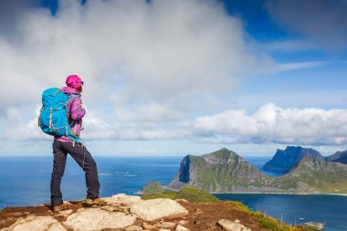 Woman hiking in mountains, enjoying Norway landscape. Lofotens. Travel, adventure, healthy lifestyle concept clipart