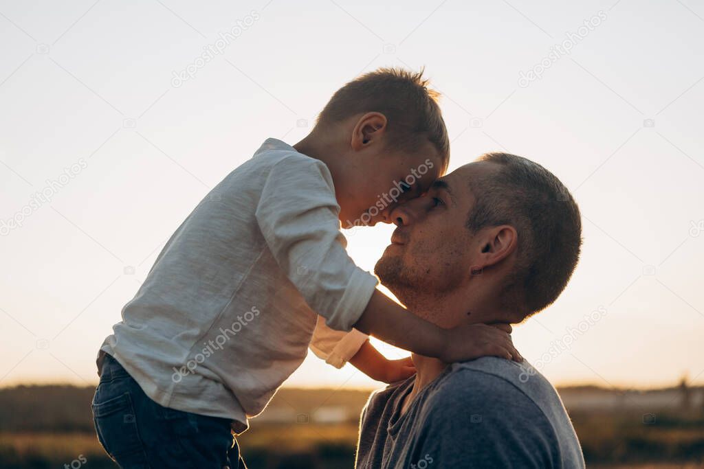 Father and son playing in the park at the sunset time. Family, trust, protecting, care, parenting, summer vacation concept