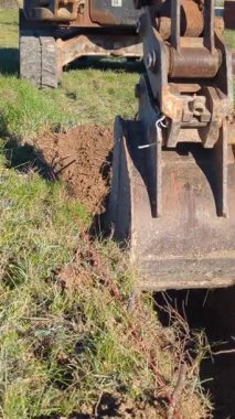 Kolu ve mini kazıcının kovası yakın plan bir temel için çukur kazıyor.