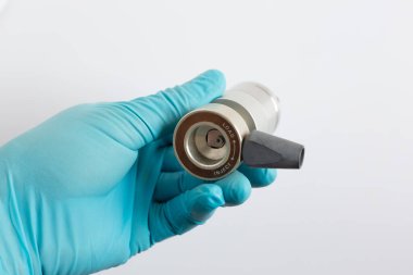 Mavi eldivenli bir bilim adamının elinde bir HPLC enjeksiyon vanası var. Görünüm beyaz arkaplanda sıvı kromatografi için yükleme ve INJECT pozisyonlarını ve örnek giriş portunu gösterir.