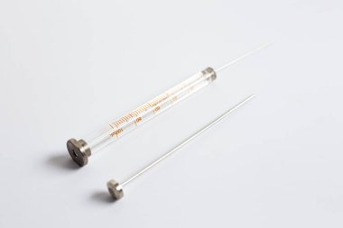 Bir bilimadamının elinde gri kauçuk tıpası ya da örnek şişelerini kapatmak için kullanılan ve arka planda hafifçe bulanıklaşan gri lastik tıpası vardır..