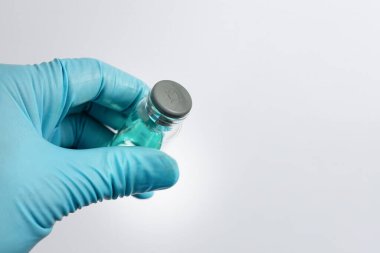 Kauçuk septumla mühürlenmiş cam örnek şişesini tutan bir bilim adamının eli, laboratuarda analiz için sıvı örneği hazırlıyor..