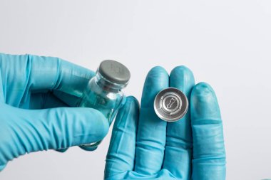 Laboratuvarda örnek hazırlanması için plastik septum ve alüminyum kriptoyla kapatılmış cam örnek şişesini tutan bilim adamının eli yakın plan..