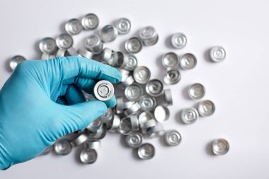 Bir bilimadamının elinde gri kauçuk tıpası ya da örnek şişelerini kapatmak için kullanılan ve arka planda hafifçe bulanıklaşan gri lastik tıpası vardır..