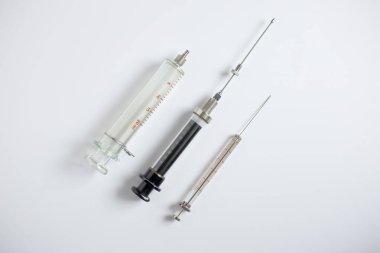 Beyaz zemin üzerinde 100 mikrolitre, 10 mL ve 20 mL şırınga dahil olmak üzere HPLC ve enstrümantal analiz için üç tip cam şırınga.