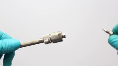 A scientist's hands in blue gloves connect a stainless steel capillary fitting to an HPLC column for liquid chromatography analysis in a science lab.