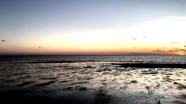 Bela praia de areia por do sol com o céu colorido refletido na praia e ondas no mar — Vídeo de Stock