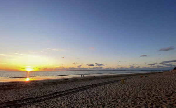 Widok zachodzącego słońca świecącego na morze i odbitego na plaży, chmury z świecącymi słońcem krawędziami. Krajobraz — Zdjęcie stockowe