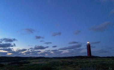 Hollanda sahilinde dramatik bir şekilde duran deniz feneri. Üzerine karanlık basınca, ya da sabaha erdiğinde,
