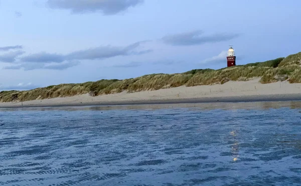 劇的なオランダの海岸に立つ灯台。その背後には色とりどりの夕暮れや明け方の空があり — ストック写真