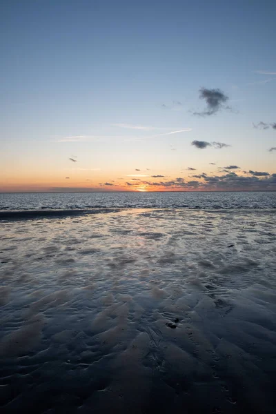 View of the setting sun shining on the Sea and reflected on the beach, clouds with sun-shining edges. Landscape — Stock Photo, Image