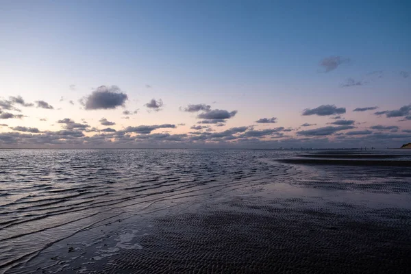 View of the setting sun shining on the Sea and reflected on the beach, clouds with sun-shining edges. Landscape