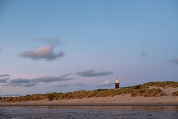 Fyren står på den holländska kusten med en dramatisk. och färgglada skymning eller gryning himlen bakom det — Stockfoto