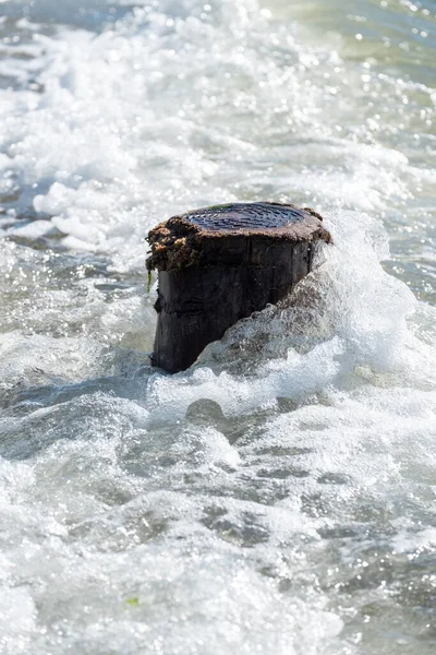 Divide ondas contra um poste de madeira no mar — Fotografia de Stock