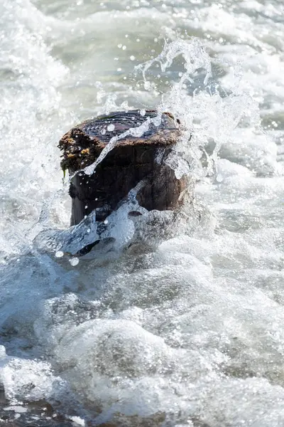 Divise les vagues contre un poteau en bois dans la mer — Photo
