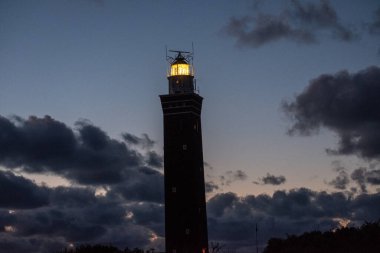 Hollanda sahilinde dramatik bir şekilde duran deniz feneri. Üzerine karanlık basınca, ya da sabaha erdiğinde,