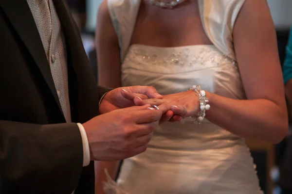 A vőlegény jegygyűrűt húz a menyasszonyok ujjára az esküvő alatt a templomban.. — Stock Fotó