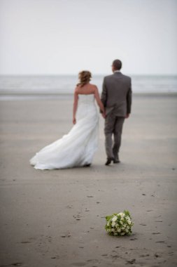 Dikkatsiz ve tanınmayan gelin ve damat sahilde yürüyorlar.
