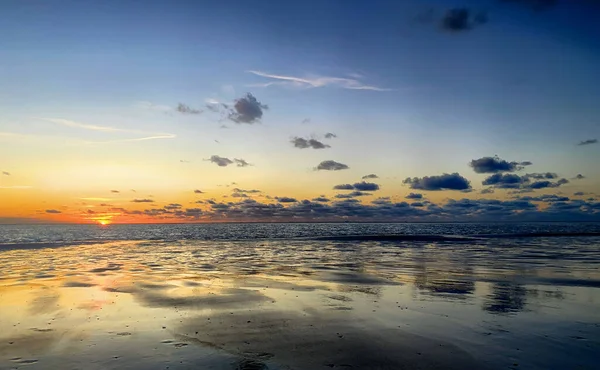 View of the setting sun shining on the Sea and reflected on the beach, clouds with sun-shining edges. Landscape