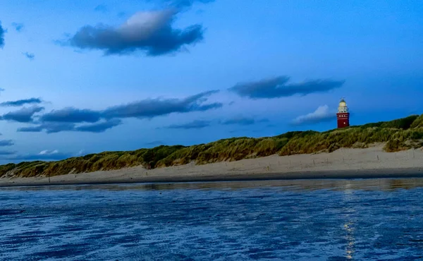 Fyren står på den holländska kusten med en dramatisk. och färgglada skymning eller gryning himlen bakom det — Stockfoto