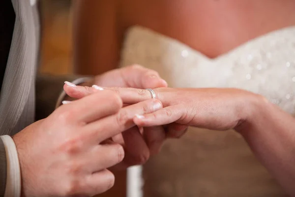Primo piano della sposa mettere una fede nuziale sul dito sposi. Coppia scambiare fedi nuziali. — Foto Stock