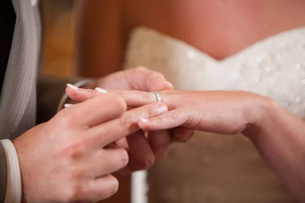 Primer plano de la novia poniendo un anillo de bodas en el dedo novios. Pareja intercambiando anillos de boda. — Foto de Stock