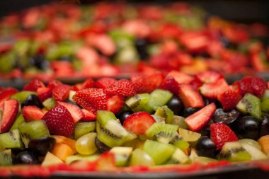 Meyve salatasıyla üzümleri, çilekleri ve kiviyi karıştırıp yakın çekim yap.