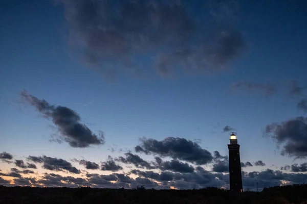 灯塔耸立在荷兰海岸上,非常引人注目.以及在它后面的五彩缤纷的暮色或黎明的天空。 — 图库照片