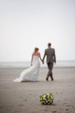 Dikkatsiz ve tanınmayan gelin ve damat sahilde yürüyorlar.