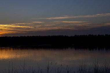 Orman gölünün üzerinde dramatik bir gün batımı
