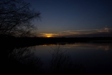 Orman gölünün üzerinde dramatik bir gün batımı