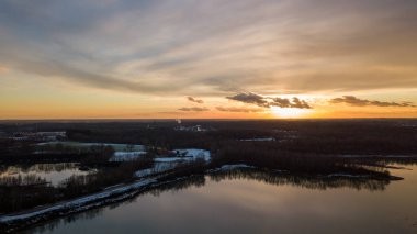 Bir orman gölü üzerinde güzel ve dramatik bir gün batımının havadan görüntüsü suya yansıyor, insansız hava aracı görüntüleri.