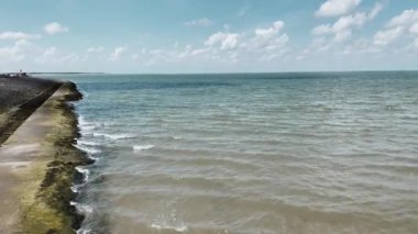 Tropikal bir ada ve kumsala çarpan ve köpüren okyanus dalgaları üzerindeki hava manzarası. Altın plajın derin mavi okyanus suyuyla buluşmasının kuşların gözündeki görüntüsü. Covid üzerine turizm kavramı.