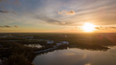 Bir orman gölü üzerinde güzel ve dramatik bir gün batımının havadan görüntüsü suya yansıyor, insansız hava aracı görüntüleri.
