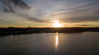 Bir orman gölü üzerinde güzel ve dramatik bir gün batımının havadan görüntüsü suya yansıyor, insansız hava aracı görüntüleri.