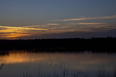 Orman gölünün üzerinde dramatik bir gün batımı