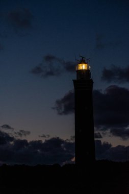 Hollanda sahilinde dramatik bir şekilde duran deniz feneri. Üzerine karanlık basınca, ya da sabaha erdiğinde,