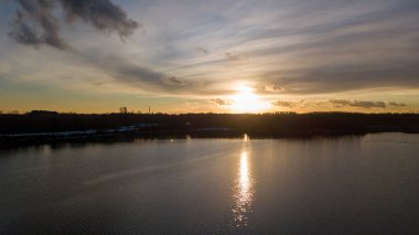 Bir orman gölü üzerinde güzel ve dramatik bir gün batımının havadan görüntüsü suya yansıyor, insansız hava aracı görüntüleri.
