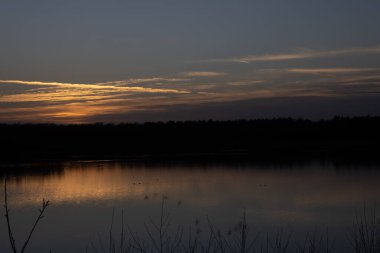 Orman gölünün üzerinde dramatik bir gün batımı