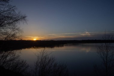 Orman gölünün üzerinde dramatik bir gün batımı