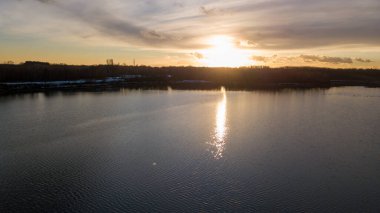 Bir orman gölü üzerinde güzel ve dramatik bir gün batımının havadan görüntüsü suya yansıyor, insansız hava aracı görüntüleri.