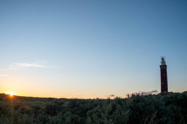 Hollanda sahilinde dramatik bir şekilde duran deniz feneri. Üzerine karanlık basınca, ya da sabaha erdiğinde,