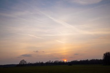 Gün batımında bulutlu bulutlu bulutlar ılık gün batımında aydınlık, renkli günbatımı gökyüzü akşam güneşiyle aydınlanan dramatik gökyüzü bulutları. Gün batımında köy yolu