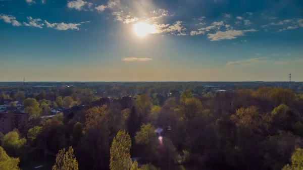 DRONE: Flygfoto av en gyllene morgonsol under soluppgång eller solnedgång belyser den spektakulära höstfärgade naturen flyger ovanför träden i en park i staden Turnhout i Belgien — Stockfoto