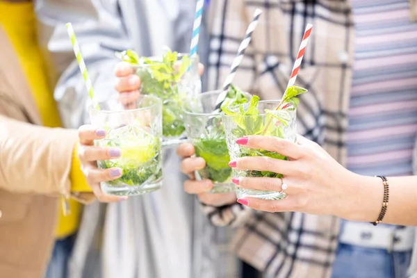 Yaşam tarzı açık hava bayan arkadaşları yazın şehirde bir açık hava büfesi restoranında kokteyl içerler. Mutlu insanlar mojito ile tezahürat yapıyor ve eğleniyorlar.