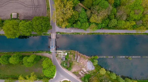 Воздушная съемка подъездного моста через канал или реку в зеленом ландшафте сельской местности во Фландрии, Бельгия — стоковое фото